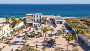 A modern resort with a pool, palm trees, and a view of the ocean.