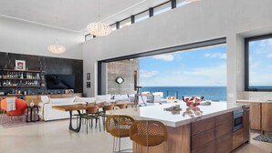 A modern kitchen with a large island, bar area, and a view of the sea. - Beachfront Estate with Full-Time Staff, Airport Transfer & Beach/Fitness Club Ac (San Jose Del Cabo)