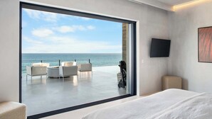 A modern hotel room with a large sliding glass door leading to a balcony with a view of the sea. - Beachfront Estate with Full-Time Staff, Airport Transfer & Beach/Fitness Club Ac (San Jose Del Cabo)