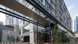 A modern building with a covered walkway, large windows, and flagpoles. - Cove The Day (Jakarta)