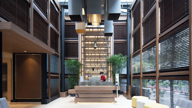 A modern lobby with a reception desk, seating area, and large windows. - Cove The Day (Jakarta)