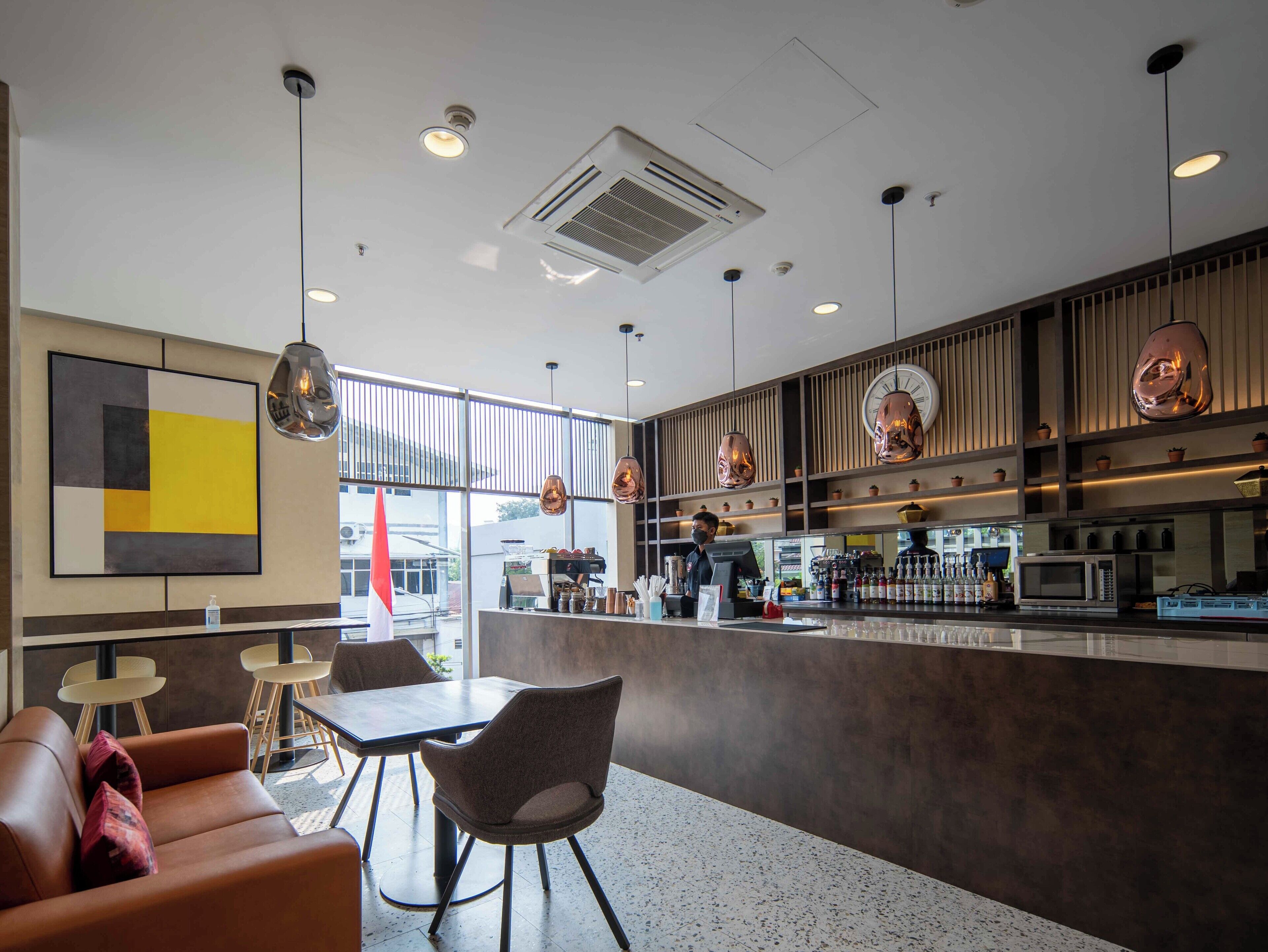 Interior moderno de una cafetería con barra, asientos y un ventanal grande.