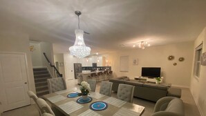 A dining area with a long table, chairs, and a chandelier. - This retreat offers a stylish, resort experience with 9b5b and a private pool (Four Corners)