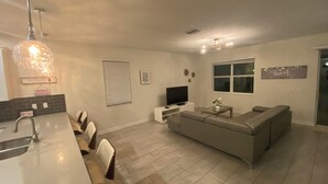 A modern kitchen with a dining area, a living room with a sofa and TV, and a large window. - This retreat offers a stylish, resort experience with 9b5b and a private pool (Four Corners)