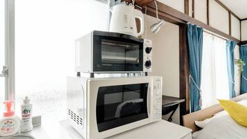 Eine Küche mit Mikrowelle und Toaster im Stapel auf einer Arbeitsplatte, ein Spülbecken und ein Fenster mit Vorhängen.