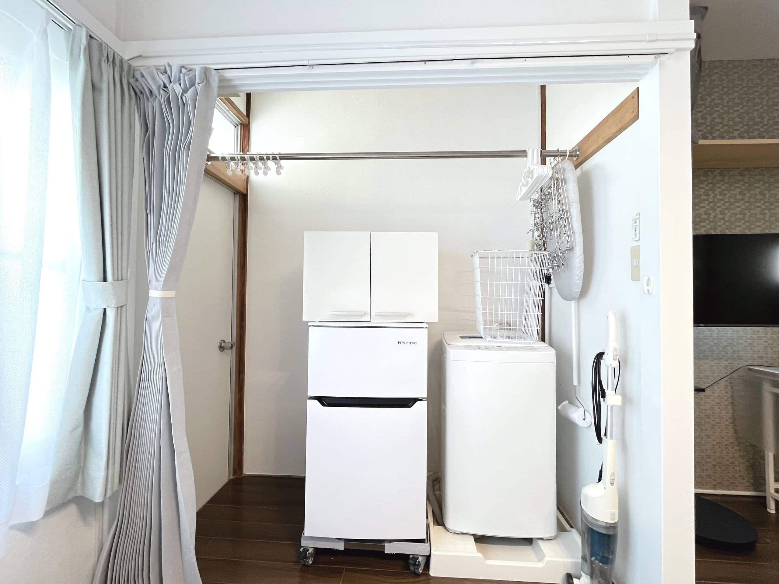 Eine kleine Küche mit Kühlschrank, Waschmaschine und Mikrowelle.