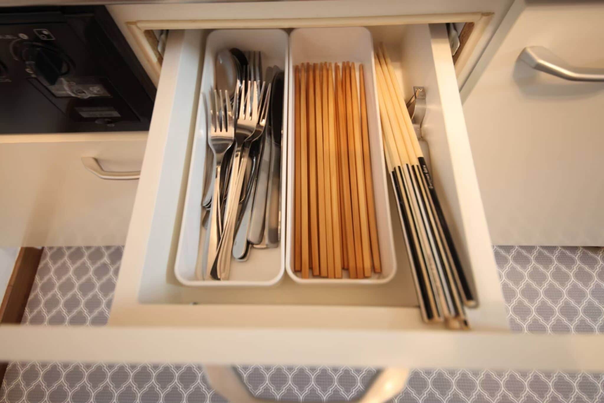 A drawer with utensils and chopsticks.