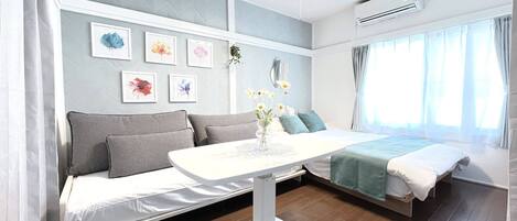 A modern bedroom with a sofa, a bed, a bedside table, and a window with curtains.