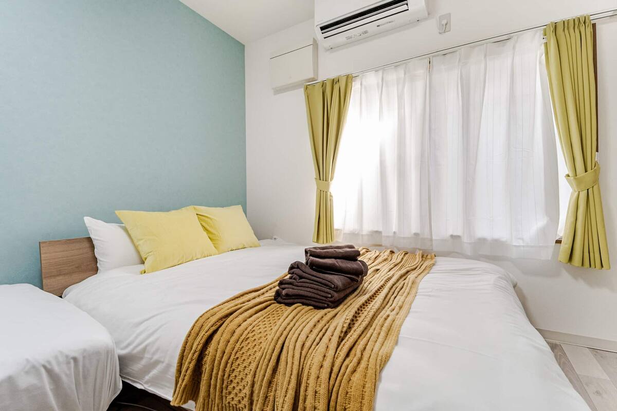 Ein Hotelzimmer mit Bett, Fenster mit Vorhängen und Klimaanlage.