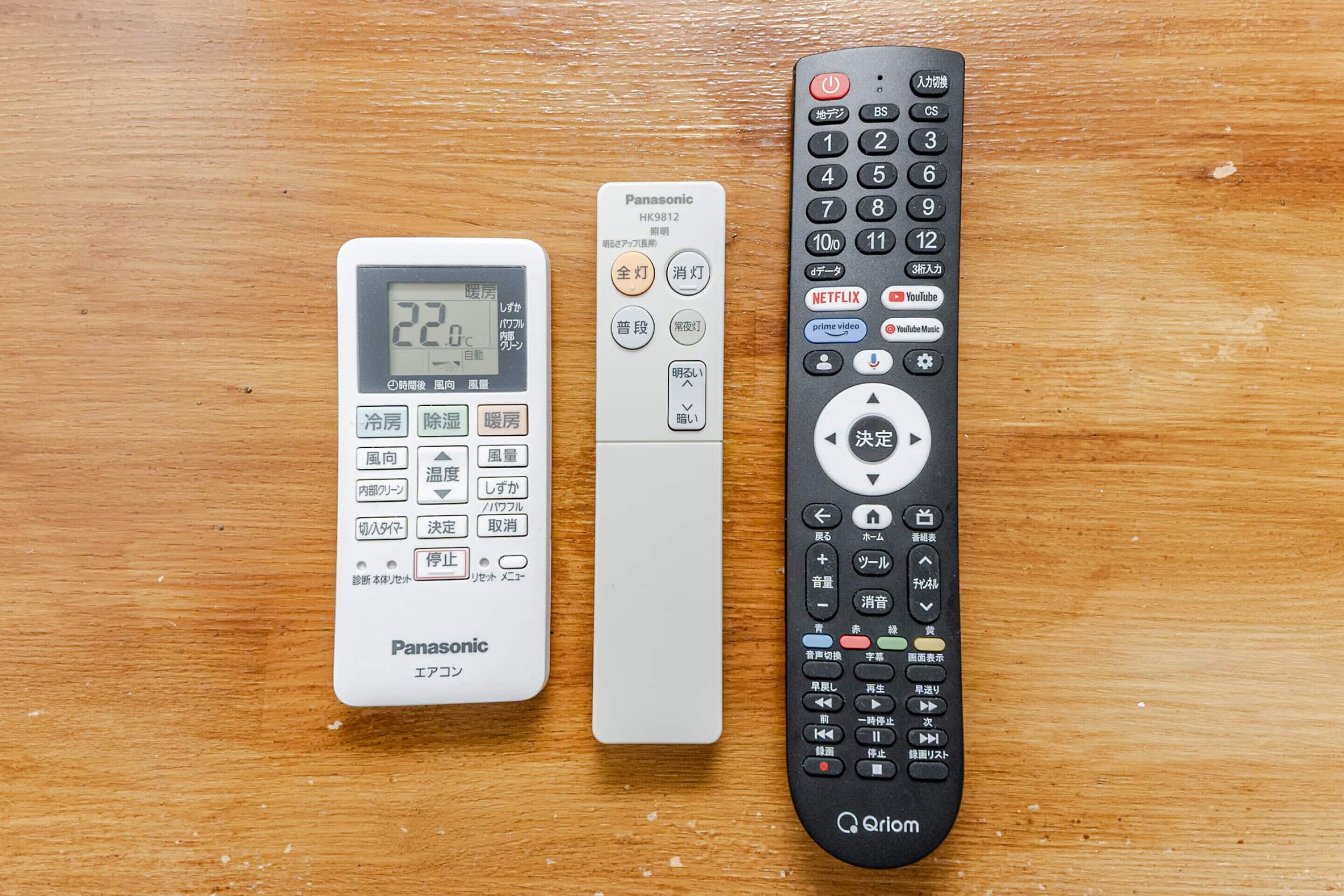 Trois télécommandes posées sur une surface en bois.