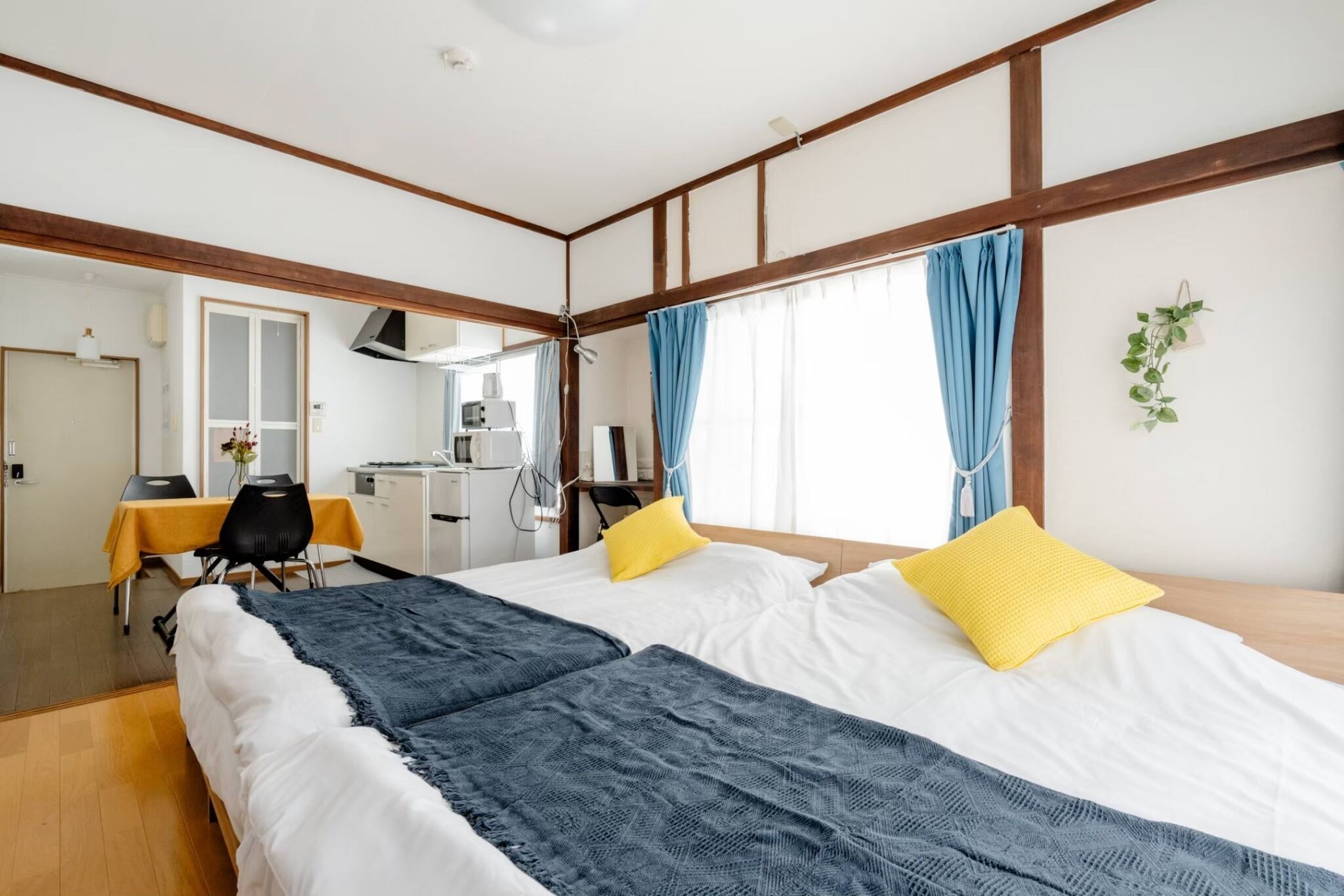 Habitación de hotel con una cama grande, un escritorio con silla, una kitchenette pequeña y un baño.
