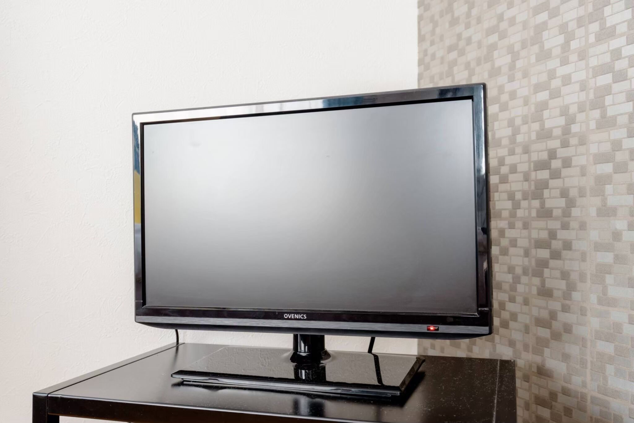 Ein Flachbildfernseher auf einem schwarzen Standfuß.