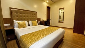 A hotel room with a large bed, a wooden headboard, a desk, and a mirror on the wall. - Hotel Pearls BKC Inn (Mumbai)