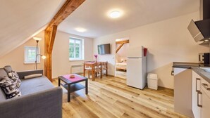 Un appartement-loft confortable comprenant un coin repas, une kitchenette et une grande fenêtre laissant entrer la lumière naturelle.