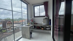 Un pequeño balcón con un lavamanos y una ventana que da a una zona residencial.