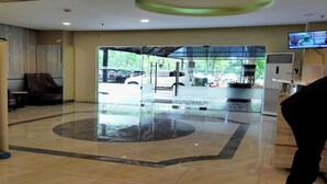 A lobby with a glass door entrance, a reception desk, and a television screen.