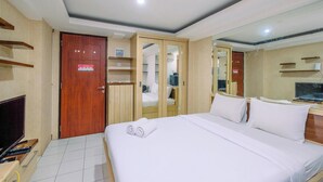 A hotel room with a bed, a TV, a desk with a computer, and a wardrobe.