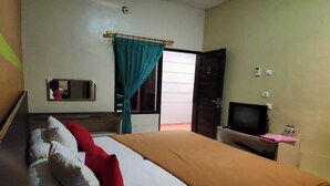 A hotel room with a bed, a television, a desk, and a door.