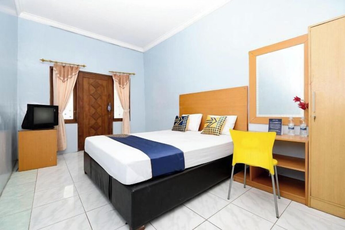 Habitación de hotel con cama, televisión, armario y una silla.