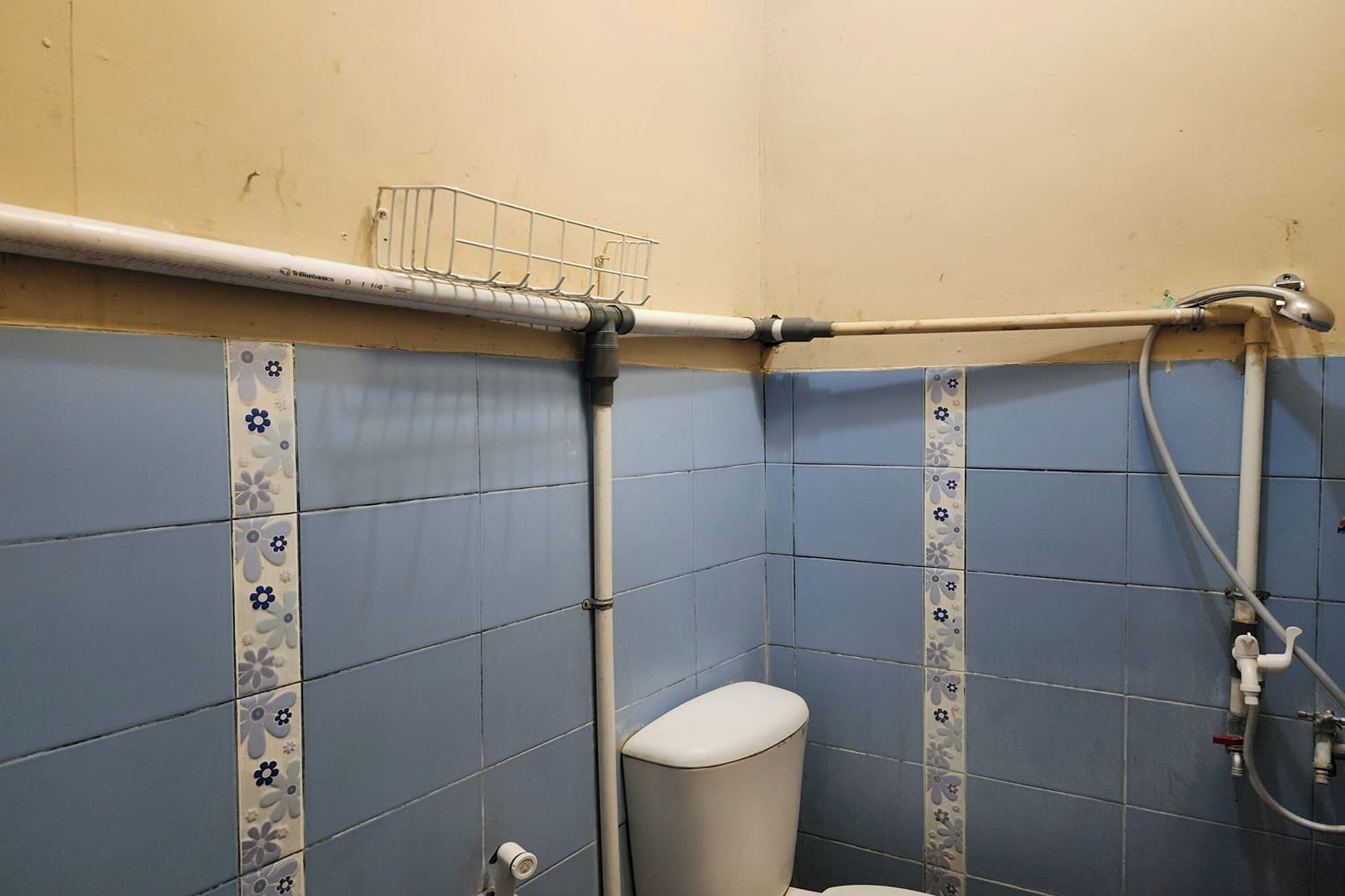 A bathroom with blue tiles, a toilet, a shower, and a towel rack.