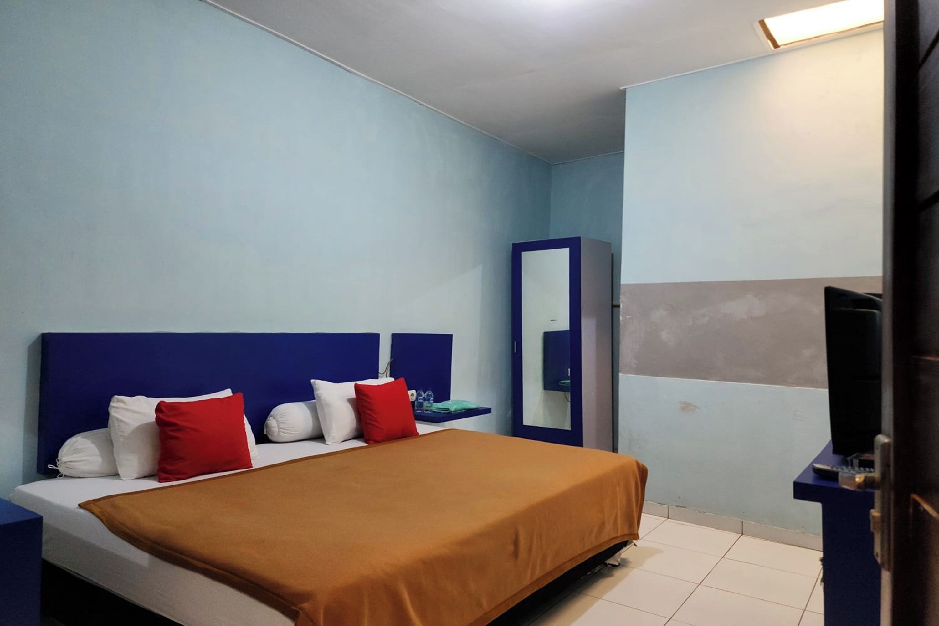 A hotel room with a bed, a wardrobe, and a television.