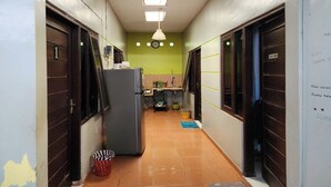A narrow hallway with a refrigerator, a sink, and a small kitchen area.