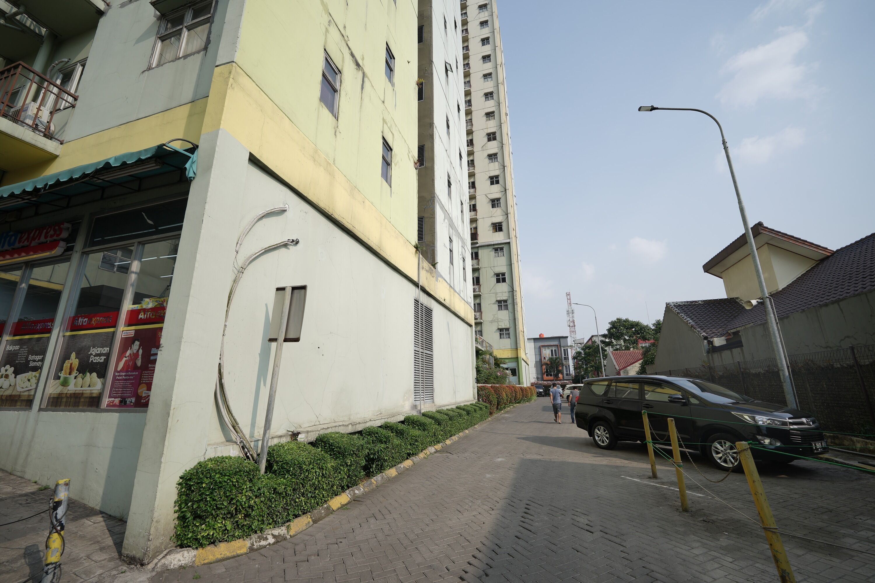 A multi-story building with a ground-floor shop and a tall residential building in the background.