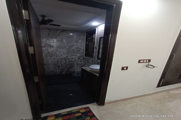 A bathroom with a marble wall, a ceiling fan, and a sink. - Mintstar Apartment And Suites, East Of Kailash (New Delhi)
