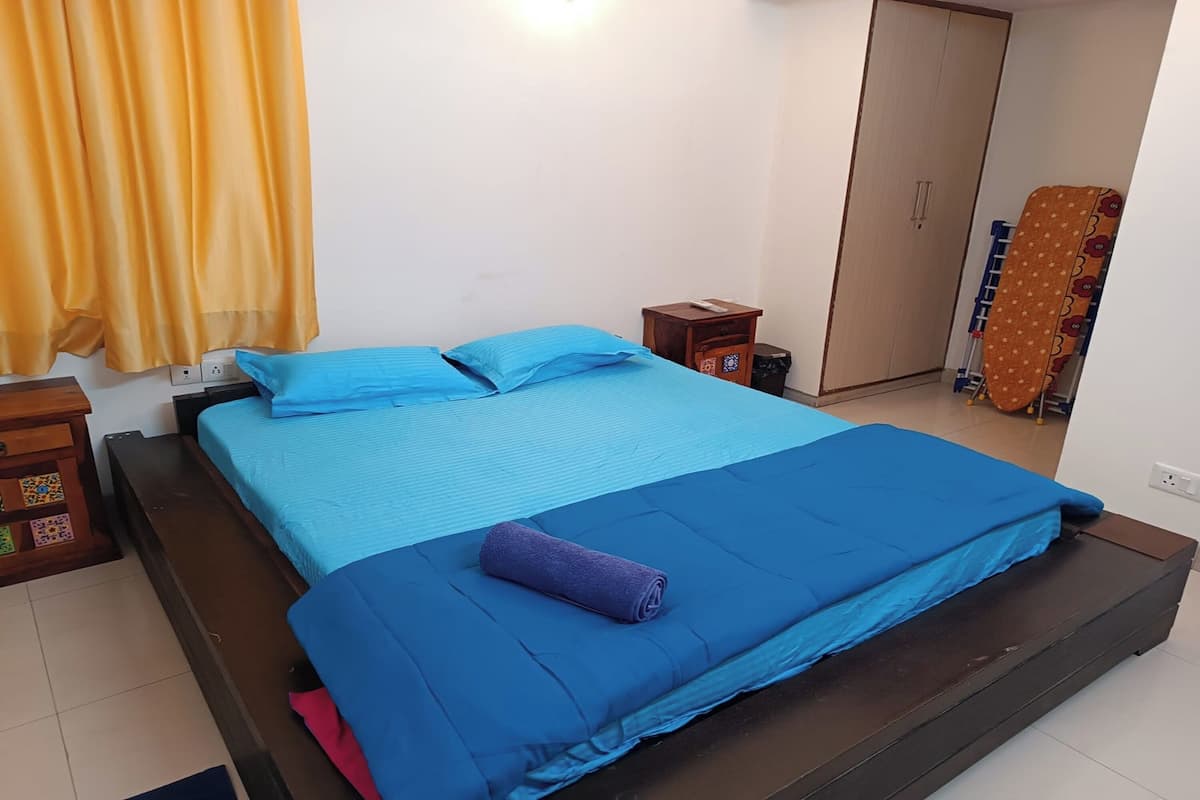 Ein Schlafzimmer mit Bett, Nachttisch, Kleiderschrank und Vorhang.