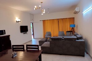 A living room with a sofa, chairs, a TV, and a dining table. - Mintstar Apartment And Suites, East Of Kailash (New Delhi)