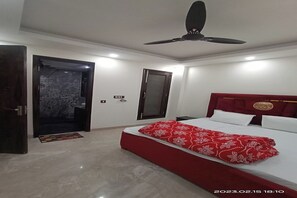 A bedroom with a bed, a ceiling fan, a door, and a wall-mounted light switch. - Mintstar Apartment And Suites, East Of Kailash (New Delhi)