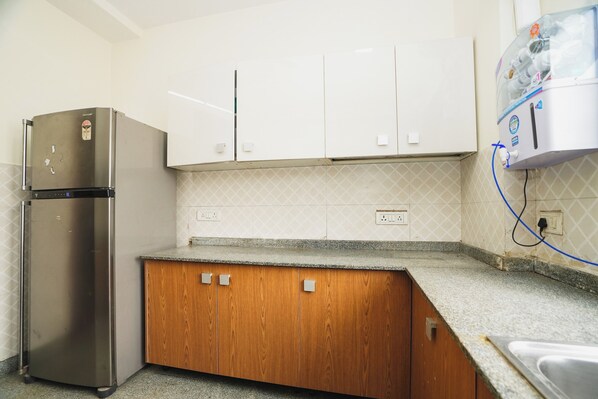 A kitchen with white cabinets, a stainless steel refrigerator, and a granite countertop.