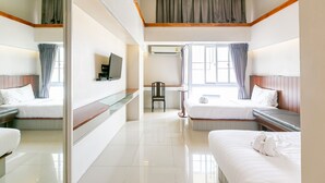 Een hotelkamer met twee bedden, een flatscreen televisie, een stoel en een raam met gordijnen.