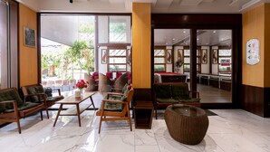 Een hotel lobby met een zithoek, een receptiebalie en uitzicht op het buitengebied.