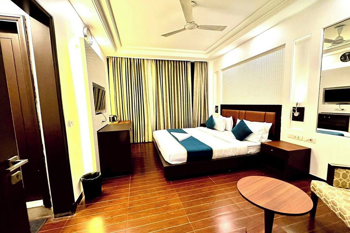 Ein Hotelzimmer mit Bett, Nachttisch, Fernseher und einem kleinen runden Tisch.