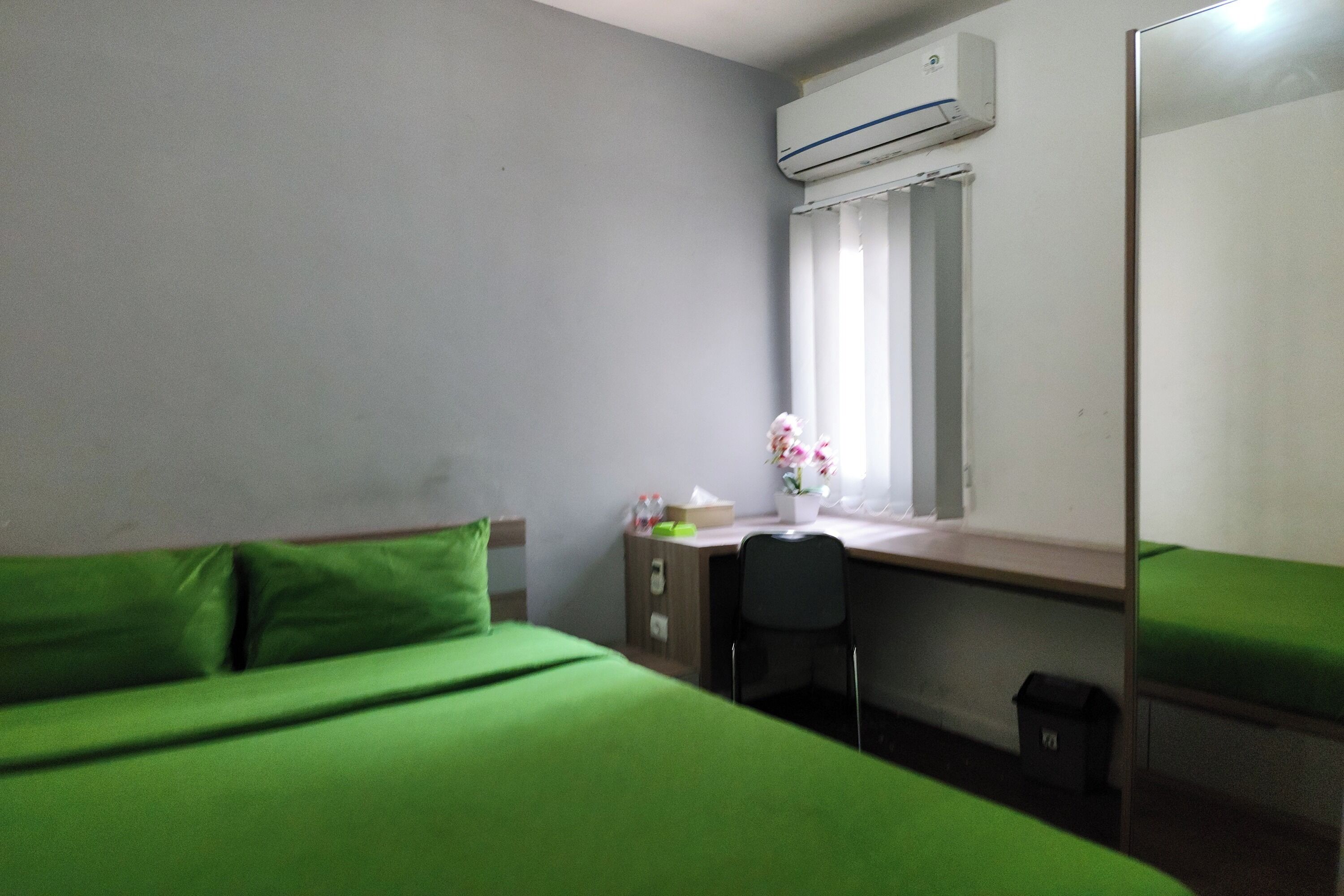 A room with a bed, a desk, a chair, and a window with curtains.