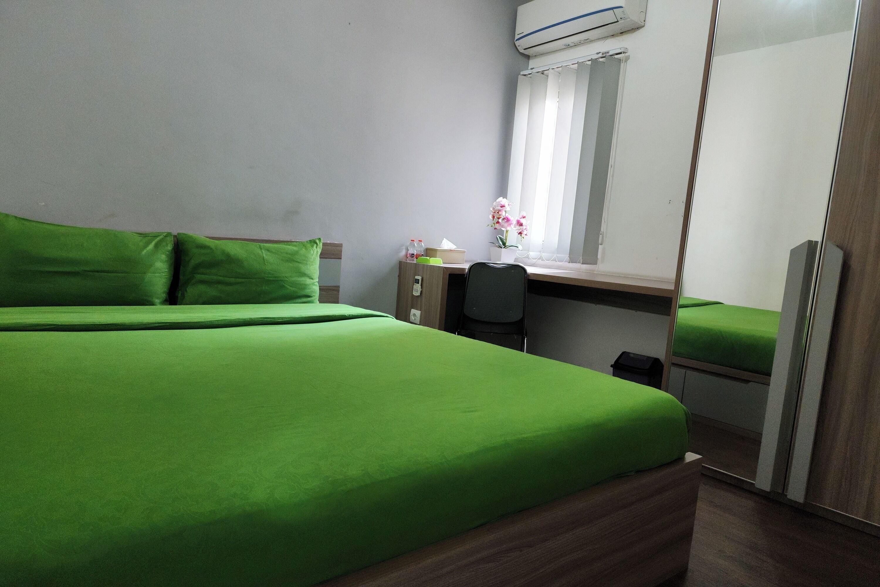 A room with a bed, a desk, a chair, and a mirror.