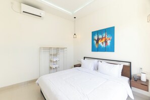 A hotel room with a bed, a wardrobe, a painting, and an air conditioning unit. - Villa Berlian (Kuta)