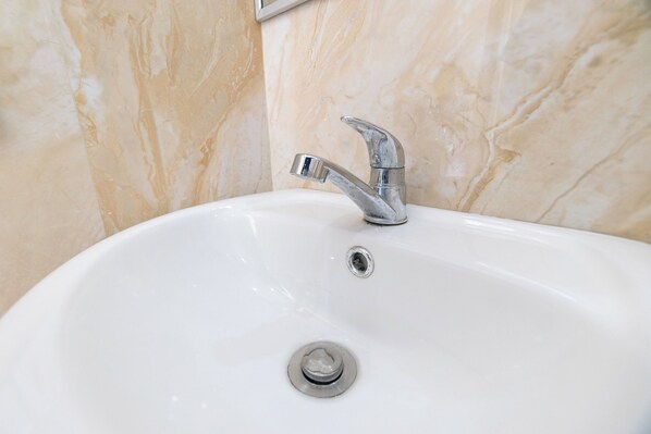 A bathroom sink with a chrome faucet and a drain.