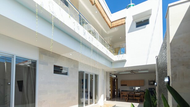 Una moderna casa a due piani con un balcone, ampie finestre e una cucina a vista.