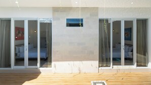 Una camera d'albergo moderna con un'ampia porta scorrevole in vetro che dà su un balcone.