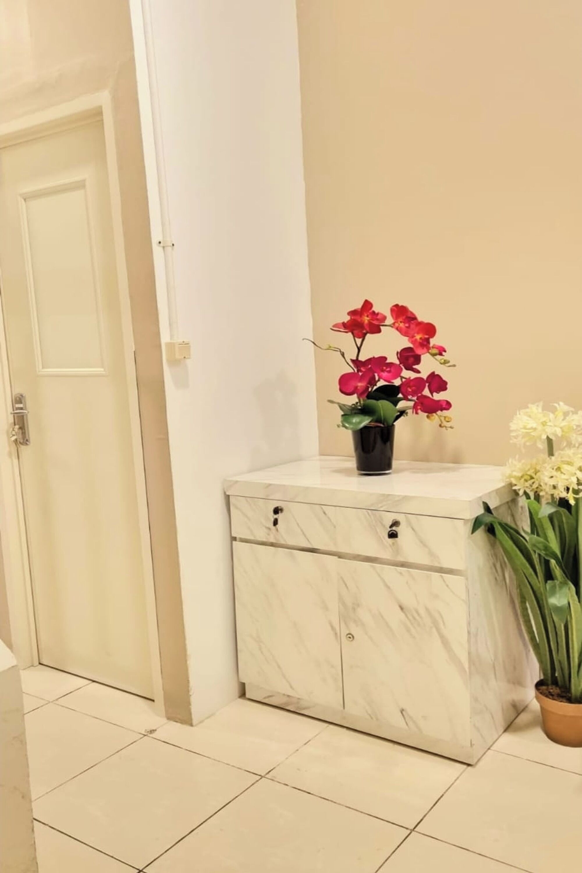 A clean, modern bathroom with a marble vanity, a potted orchid, and a potted plant.