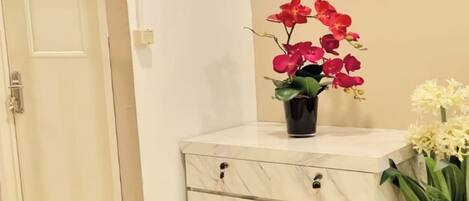 Un baño limpio y moderno con tocador de mármol, una orquídea en maceta y otra planta en maceta.