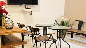A dining area with a TV mounted on the wall, round tables, and chairs. - Heritage Home (Gading Serpong)