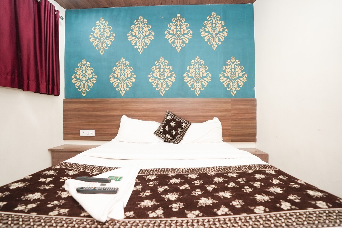 A neatly made bed with a patterned bedspread, a decorative wall hanging, and a wooden headboard.