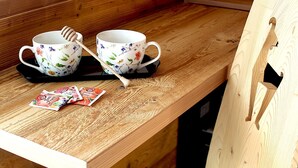 Un banco de madera con dos tazas florales y un gotero de miel, junto con bolsitas de té sobre una superficie de madera.
