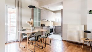 A modern kitchen with a dining area, featuring a wooden table, chairs, and a pendant light. - Harmonious 2BR Apartment in Exarchia (Athens)