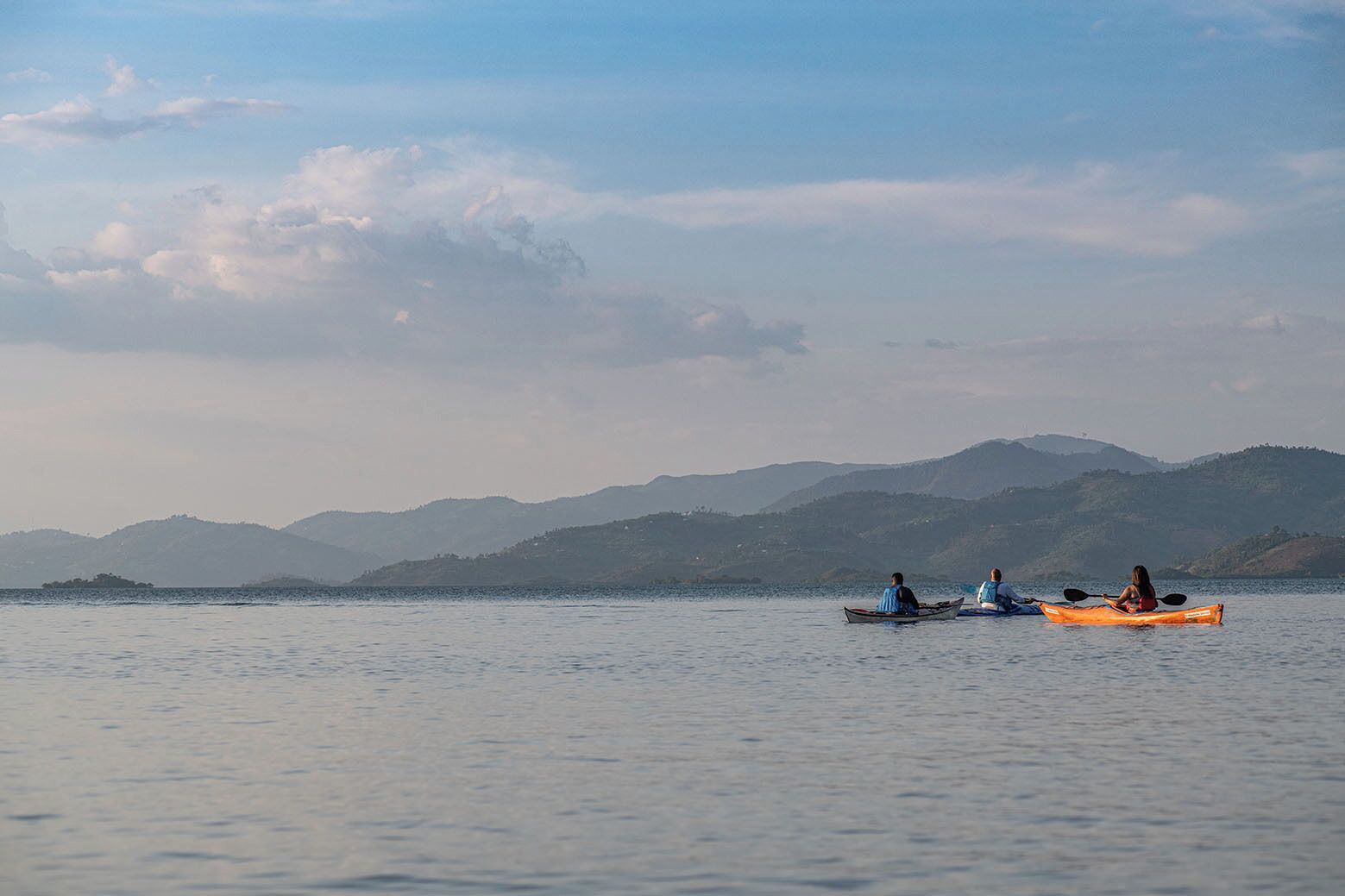 Un lago tranquilo con kayaks, montañas distantes y un cielo despejado.