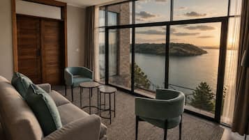 A room with a large window, a sofa, two chairs, a small table, and a ceiling fan.