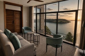 Una habitación con un ventanal grande, un sofá, dos sillones, una mesita y un ventilador de techo.
